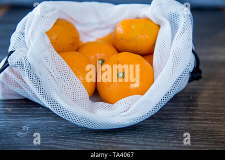 Mandarinen aus dem Supermarkt gekauft in einer wiederverwendbaren produzieren Beutel upcycled aus einem weichen Kunststoff Taschen. Umweltfreundliche Wahl. Stockfoto