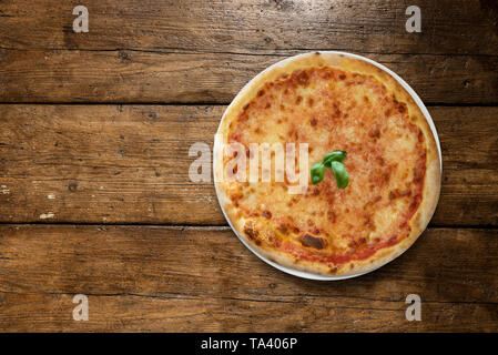 Pizza Margherita mit Basilikum auf hölzernen Tisch Stockfoto