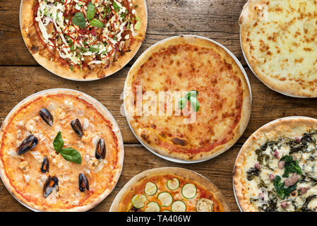 Vielzahl von Pizza auf hölzernen Tisch Stockfoto