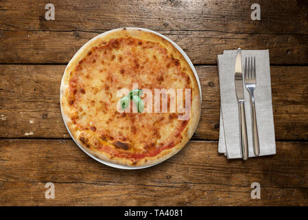 Pizza Margherita mit Basilikum auf Holztisch mit Besteck Stockfoto