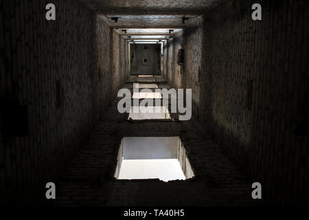 Aufzugsschacht eines großen Industrieanlage zum Zeitpunkt der Abriss. Ansicht von unten auf die Durchgänge der Böden der Lastenaufzug. Hintergrund. Stockfoto