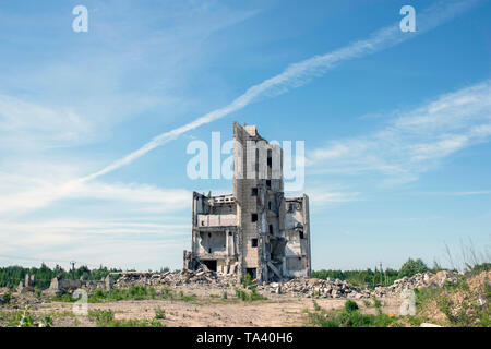 Die zerstörten Gebäude unter Abriss gegen die strukturierte blauer Himmel mit weißen Wolken und eine Spur des fliegenden Flugzeug. Hintergrund. Stockfoto