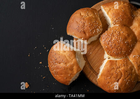 Frisch gebackene Weiche süße Brötchen geteilt mit Sesam, abgerissene Stück Brot Stockfoto