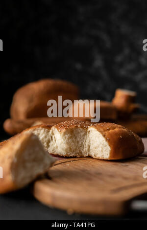 Frisch gebackene Weiche süße Brötchen geteilt mit Sesam, abgerissene Stück Brot Stockfoto