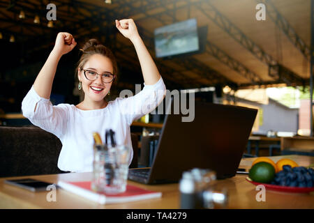 Porträt der glückliche junge geschäftsfrau Erfolg feiern mit den Armen vor Laptop. Gemischte Rasse asiatischen kaukasisch Weiblich gewann eine Menge Geld in Lo Stockfoto