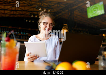 Geschäftsfrau aus der Ferne im Cafe mit Headset und Laptop arbeiten. Gemischte Rasse weiblich Durchführung von Verhandlungen auf der Konferenz video chat. Telecommu Stockfoto