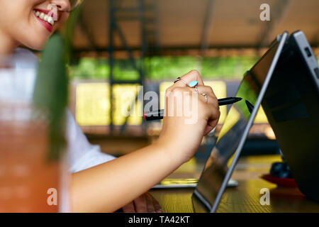 Isolierte schließen Seitenansicht Freiberufler Frau Zeiger mit Stift auf Convertible Notebook Bildschirm im Zelt. Mädchen mit 2 in 1 Notebook mit Touch Stockfoto