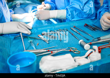 In der Nähe von Doktor Hände während der Operation in Betrieb. Sterilen chirurgischen Instrumenten in einem realen Betrieb verwendet. Schwerpunkt liegt auf der Zeile der Klemmung Griffe. Stockfoto