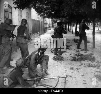 Eine Truppe von Deutschen Infanteristen während einer überraschung Feuer Angriff in einer russischen Stadt. Die Soldaten im Vordergrund sind nur über die Mg-34 th das Bild wahrscheinlich in der Ukraine gemacht wurde, neu zu laden. Stockfoto