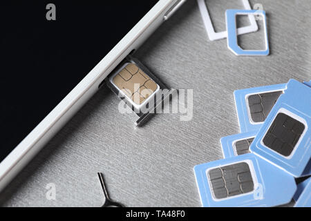 Mobiltelefon mit SIM-Karten auf grauem Hintergrund, Nahaufnahme Stockfoto