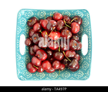 Frische reife Bing Kirschen in eckigen Aqua und weiße Schüssel auf weißem in flachen isolierten legen Zusammensetzung. Stockfoto