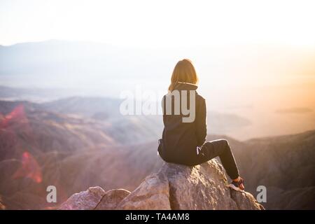 Eine Frau, die auf einem Berggipfel sitzt Stockfoto