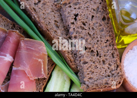 Snack mit selbstgemachten Roggenbrot und getrocknet Schweinefleisch auf einem braunen Ton Platte close-up Stockfoto