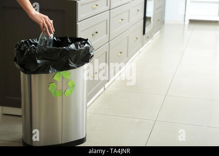 Junge Frau werfen leere Plastikflasche in Papierkorb zu Hause. Recycling Konzept Stockfoto