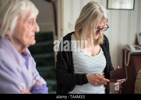 Mutter ist traurig - nach einem Besuch ihre ältere und Sehbehinderte Mutter zu sehen, die Tochter Umarmungen und Abschied von ihrer Mutter, bevor ihr lange driv Stockfoto