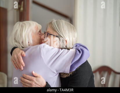 Nach einem Besuch ihre ältere und Sehbehinderte Mutter zu sehen, die Tochter Umarmungen und Abschied von ihrer Mutter, bevor Ihre lange Fahrt zurück nach Hause. Stockfoto