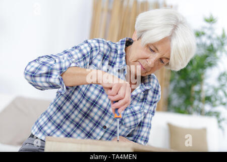 Reife Frau Montage Bett im neuen Zuhause Stockfoto