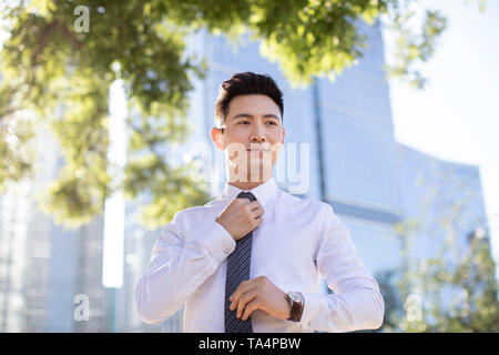 Zuversichtlich, dass junge Unternehmer das Binden einer Krawatte Stockfoto