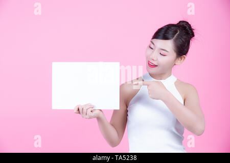 Schöne Frau mit einem White Board Blatt auf einem rosa Hintergrund. Stockfoto