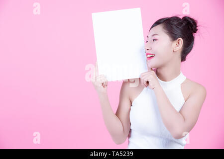 Schöne Frau mit einem White Board Blatt auf einem rosa Hintergrund. Stockfoto