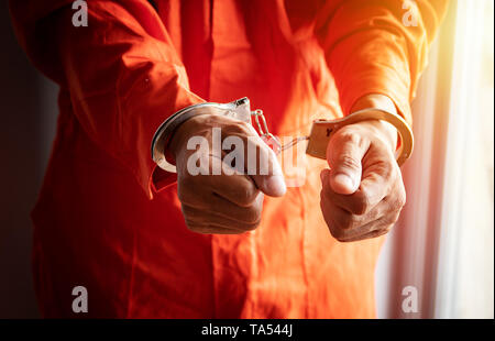 Nahaufnahme der Gefangenen die Hände mit Handschellen in orange Overall am Gefängnis Stockfoto