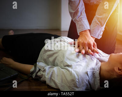 Freiwillige Büro Mann verwenden Sie die Handpumpe an der Brust für Erste Hilfe Notfall HLW auf Herzinfarkt Frau bewusstlos, versuchen Patienten Frau bei der Arbeit Reanimation Stockfoto