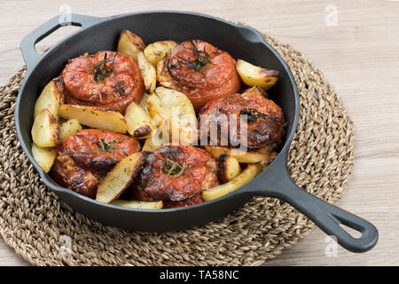 Gusseisernen Pfanne mit Tomaten mit Reis und gebackene Kartoffeln auf Mittelstück und hellen Hintergrund Stockfoto