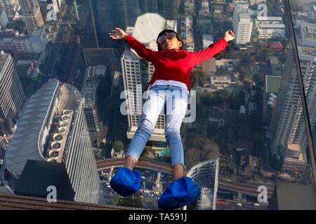 Kleines Mädchen liegt auf dem Glas Skywalk, Glas Stock auf der Aussichtsplattform des Maha Nakhon Tower, Bang Rak District, Bangkok, Thailand Stockfoto