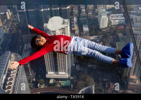 Kleines Mädchen liegt auf dem Glas Skywalk, Glas Stock auf der Aussichtsplattform des Maha Nakhon Tower, Bang Rak District, Bangkok, Thailand Stockfoto