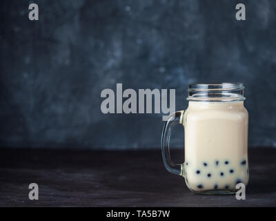Hausgemachte Milch Bubble Tea mit Tapioka Perlen Kugeln. Beliebte Taiwan Bubble Tea in Glas Marmeladenglas mit Kopie Platz für Text. Bubble Tea auf dunklen backgrou Stockfoto