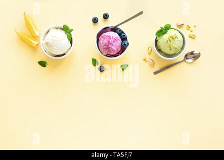Eis Sortiment. Verschiedene Früchte und Beeren Eis auf gelbem Hintergrund, kopieren. Gefrorener Joghurt oder Eis - gesunde Sommer Nachtisch. Stockfoto