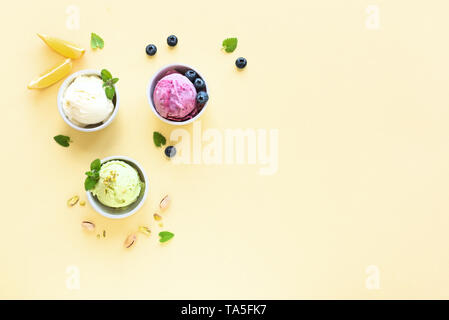 Eis Sortiment. Verschiedene Früchte und Beeren Eis auf gelbem Hintergrund, kopieren. Gefrorener Joghurt oder Eis - gesunde Sommer Nachtisch. Stockfoto