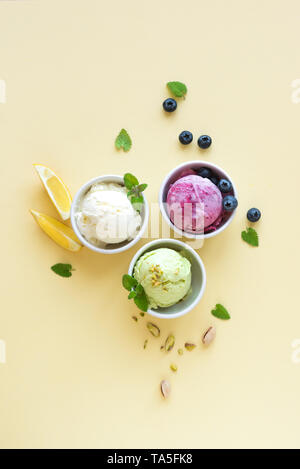 Eis Sortiment. Verschiedene Früchte und Beeren Eis auf gelbem Hintergrund, kopieren. Gefrorener Joghurt oder Eis - gesunde Sommer Nachtisch. Stockfoto