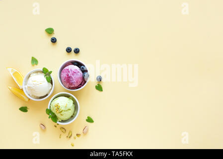 Eis Sortiment. Verschiedene Früchte und Beeren Eis auf gelbem Hintergrund, kopieren. Gefrorener Joghurt oder Eis - gesunde Sommer Nachtisch. Stockfoto