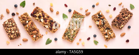 Granola Bars Sortiment auf rosa Hintergrund, Banner. Hausgemachten gesunden Snack - Müsli superfood Bars. Stockfoto