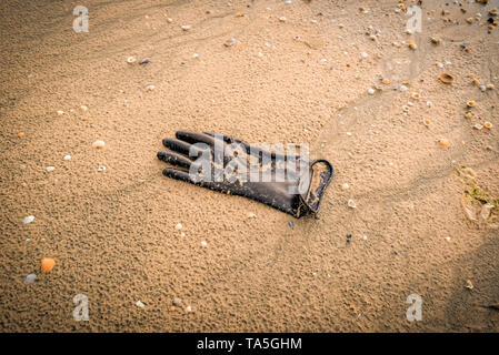 Handschuh auf den Strand/Meer Wasserverschmutzung mit Kunststoff Handschuh auf Sand am Strand die Erde retten Konzept Stockfoto