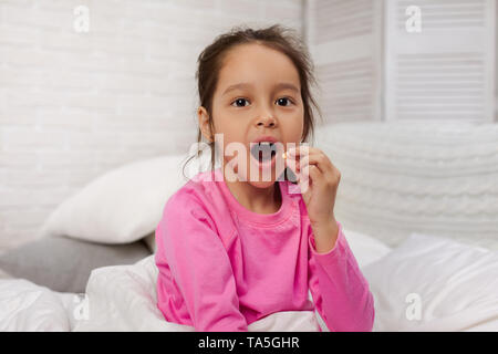 Kleines Kind Mädchen essen Pille für die Behandlung Stockfoto