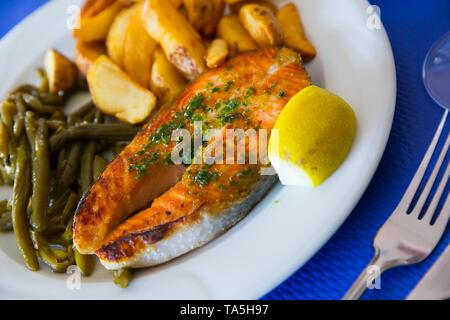 Gebratenes Lachsfilet mit gebackenen Kartoffeln und grüne Bohnen serviert. Stockfoto