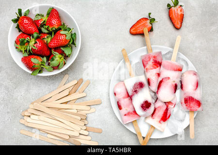 Natürliche saftige Erdbeere Eis am Stiel mit Joghurt. Erfrischendes eis Pops, Overhead, flach Stockfoto