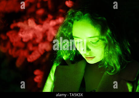 Portrait von einer geheimnisvollen Frau in grün Beleuchtung mit coral Hintergrund Stockfoto