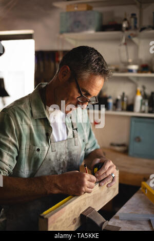 Reifen Tischler messen ein Holzbrett in der Werkstatt Stockfoto