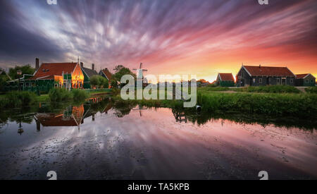 Traditionelle holländische Windmühle in der Nähe des Kanals. Niederlande, Landcape bei Sonnenuntergang Stockfoto