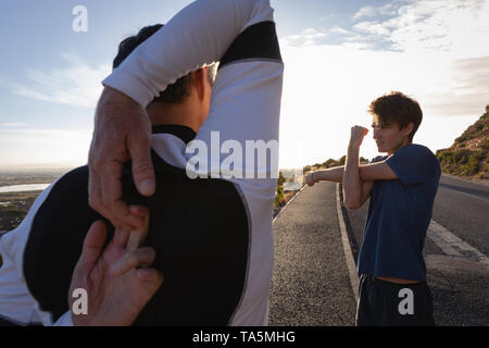 Vater und Sohn zu tun stretching Übung auf der Straße Stockfoto