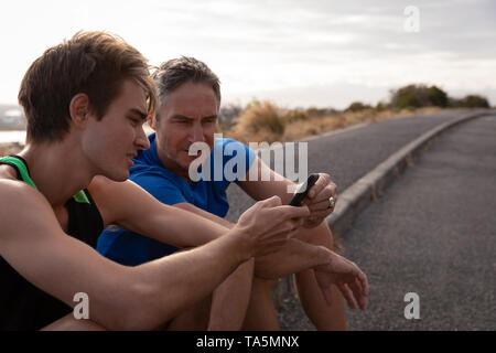 Vater und Sohn Blick auf Handy Stockfoto