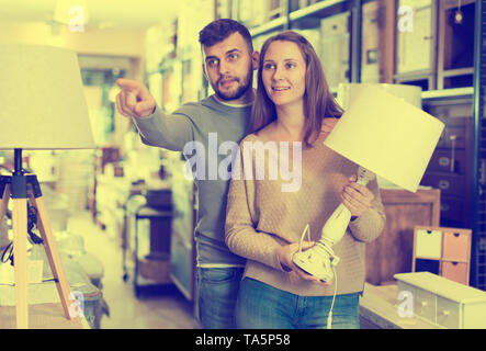 Junges Paar Auswahl Tischleuchte für Wohnung in Möbeln store Stockfoto