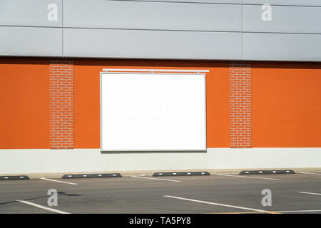 Horizontalen weißen Hinweistafel auf ein Gebäude der Wand neben der leeren Parkplatz Stockfoto