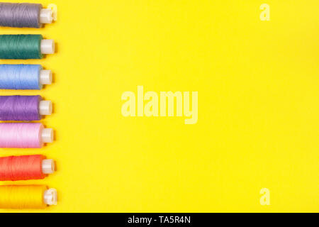 Handwerk Hintergrund. Eingestellt von bunten Spulen des Gewindes auf gelbem Hintergrund mit kopieren. Zubehör für Handarbeiten, Sticken, Nähen. Stockfoto
