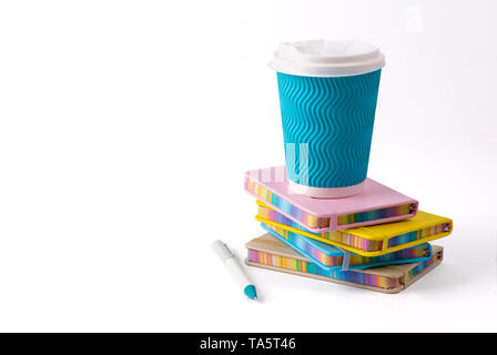 Blaues Papier Kaffeetasse, Stift und Notizblock auf weißem Hintergrund. Weibliche Arbeitsbereich Konzept Stockfoto