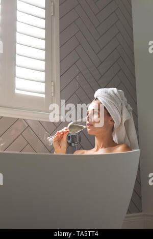 Schöne Frau mit Champagner in der Badewanne. Stockfoto