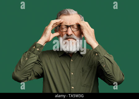 Unglückliche Menschen mit geschlossenen Augen versuchen, einige Informationen, Tatsachen zu erinnern, halten seine Schläfen, Mann mit grauen Bart hat sein Gedächtnis verloren. Grün isoliert Stockfoto